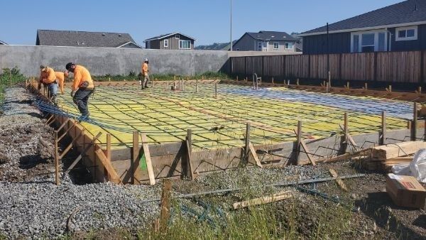 Armerad grundplatta med isolering och byggarbetare under konstruktion